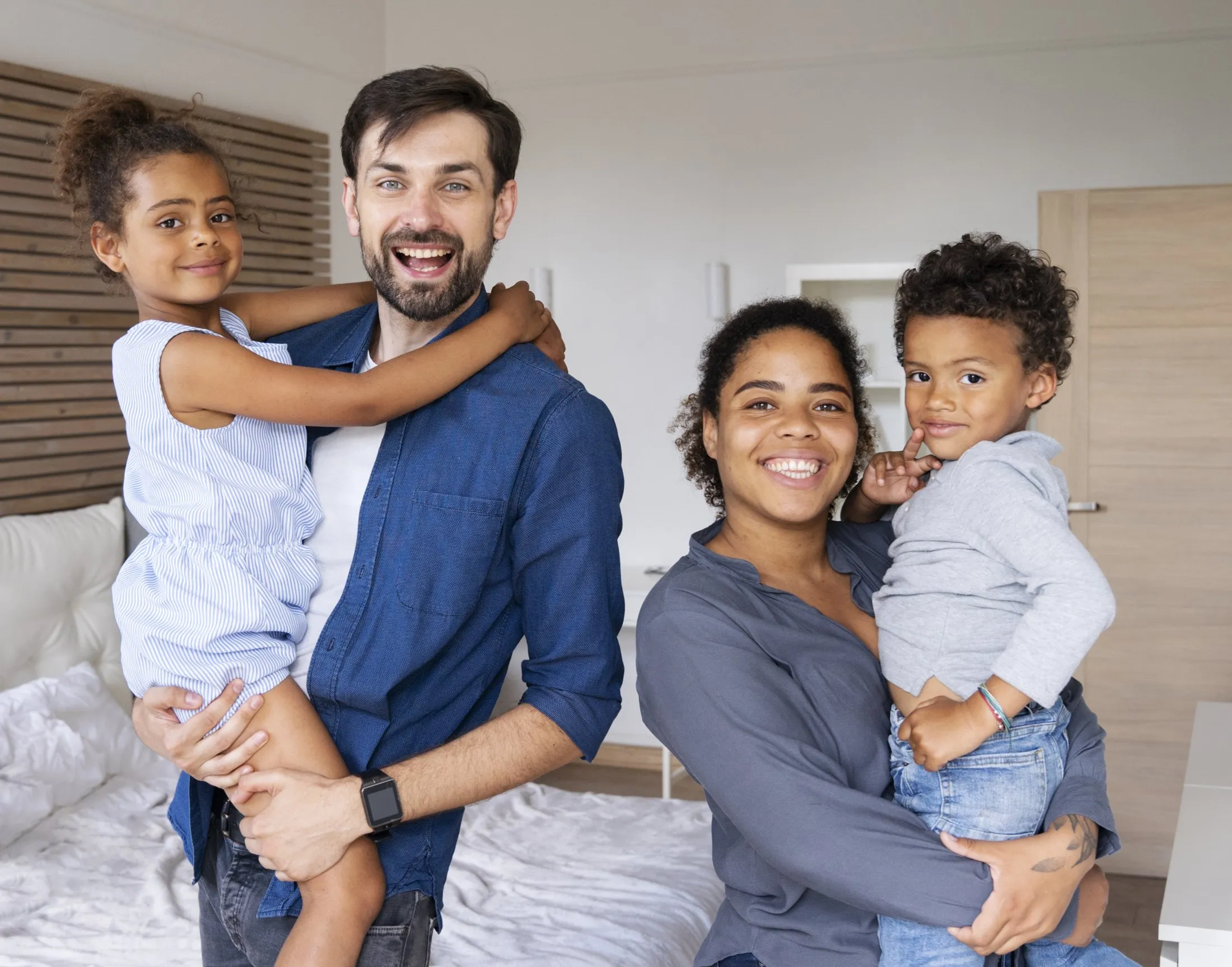 Família sorrindo em casa, pais com os dois filhos no colo