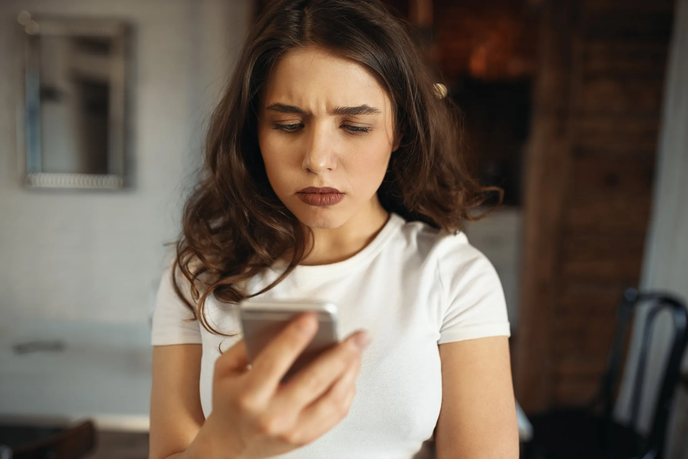 Mulher olhando o celular com expressão preocupada